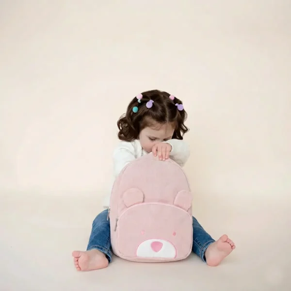 Bambina apre lo zainetto a forma di orsetto rosa confetto