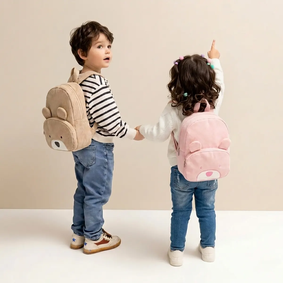 Due bambini indossano gli zainetti a forma di orsetto sulle spalle