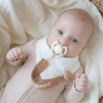 Neonato con ciuccio agganciato a catenella ferma ciuccio in mussola marrone nocciola