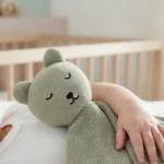 Neonato tiene il doudou in maglia verde chiaro