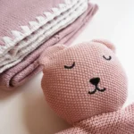 Dettaglio della copertina e del doudou in maglia del kit regalo neonato rosa sorbetto