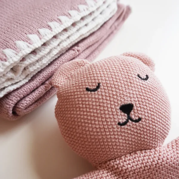 Dettaglio della copertina e del doudou in maglia del kit regalo neonato rosa sorbetto