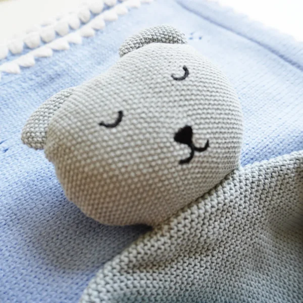Dettaglio della copertina e del doudou in maglia azzurro del kit nascita