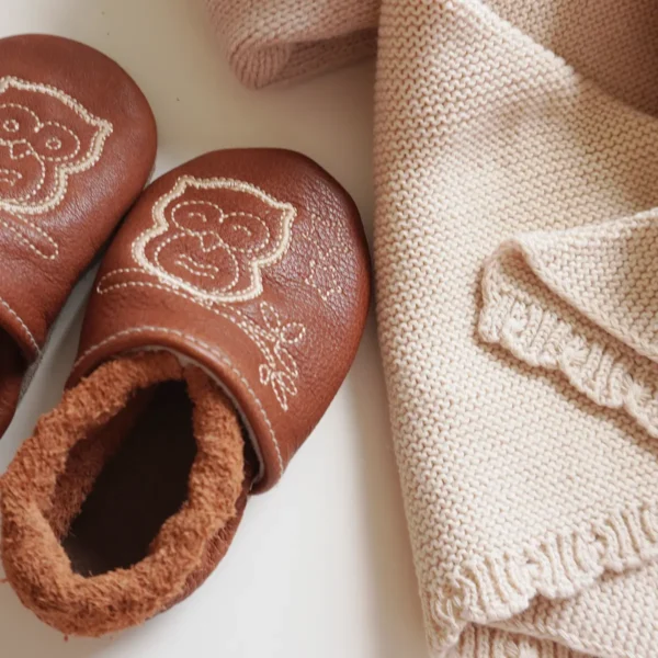 Dettaglio scarpine per gattonare con ricamo gufo in pelle naturale e doudou in maglia di cotone inclusi nel kit regalo nascita